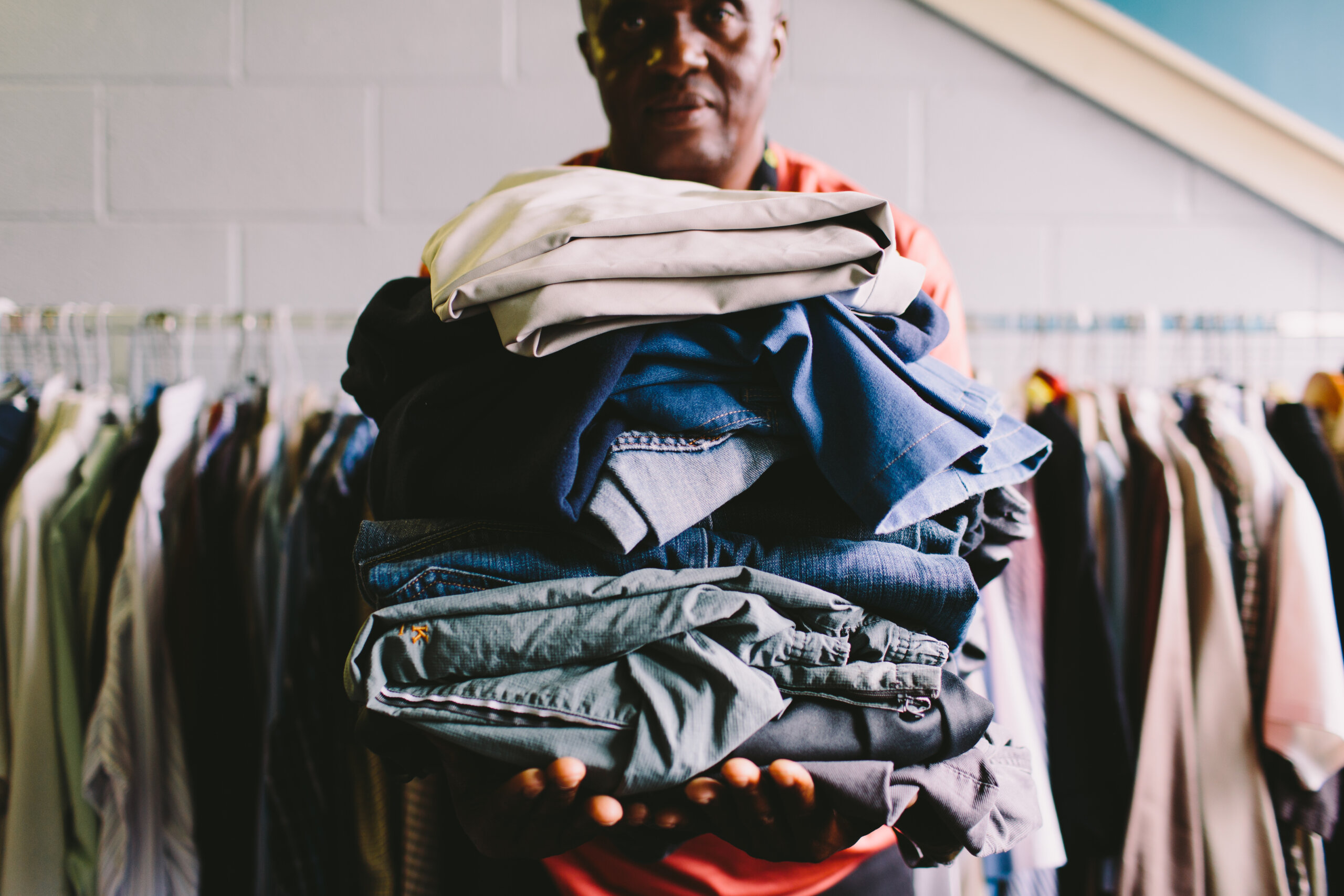 man holding stack of clothes
