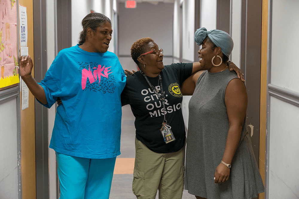 three women laughing with arms around each other