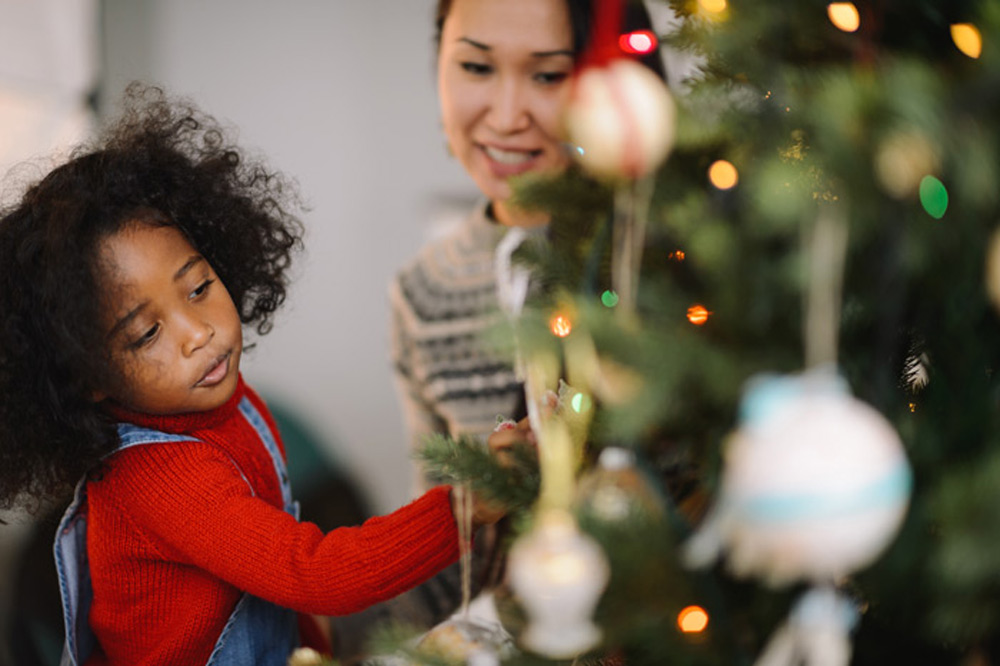 two people surrounding christmas tree