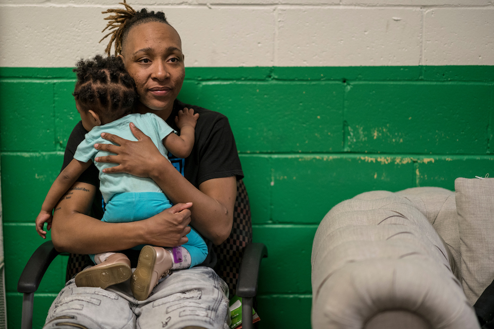 Homelessness Doesn’t Always Mean Living on the Streets as seen by this woman holder her child inside a shelter