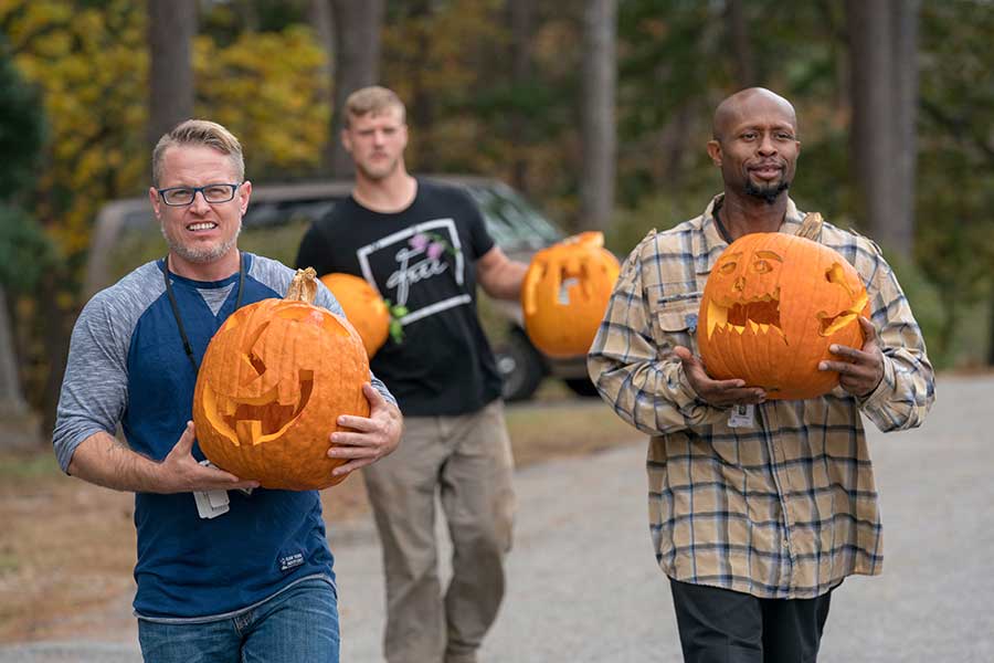 Photo of clients at The Potter's House holding carved pumpkins