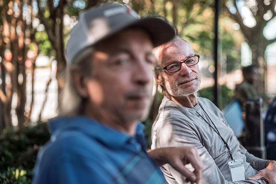Two men sitting in the shade on a bench