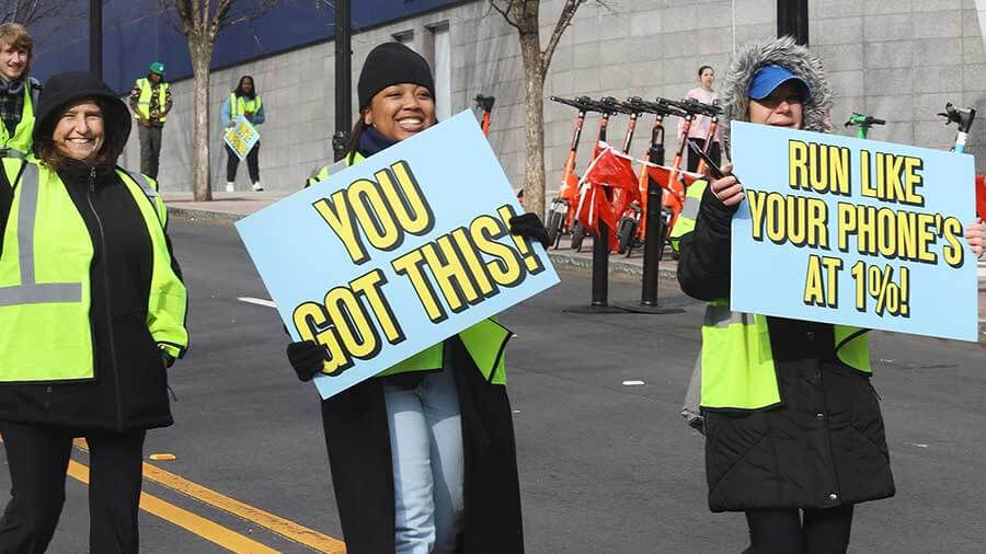 Volunteers holding signs encouraging runners